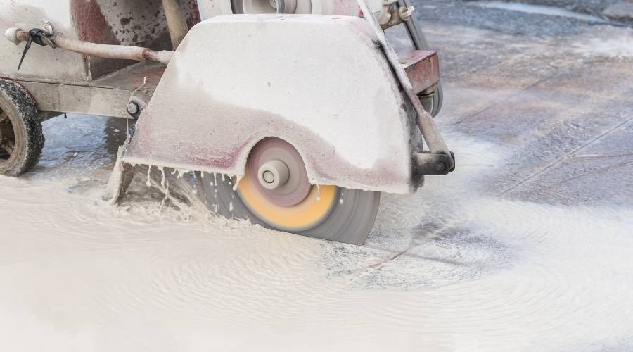 Worker cutting concrete road with diamond saw blade machine